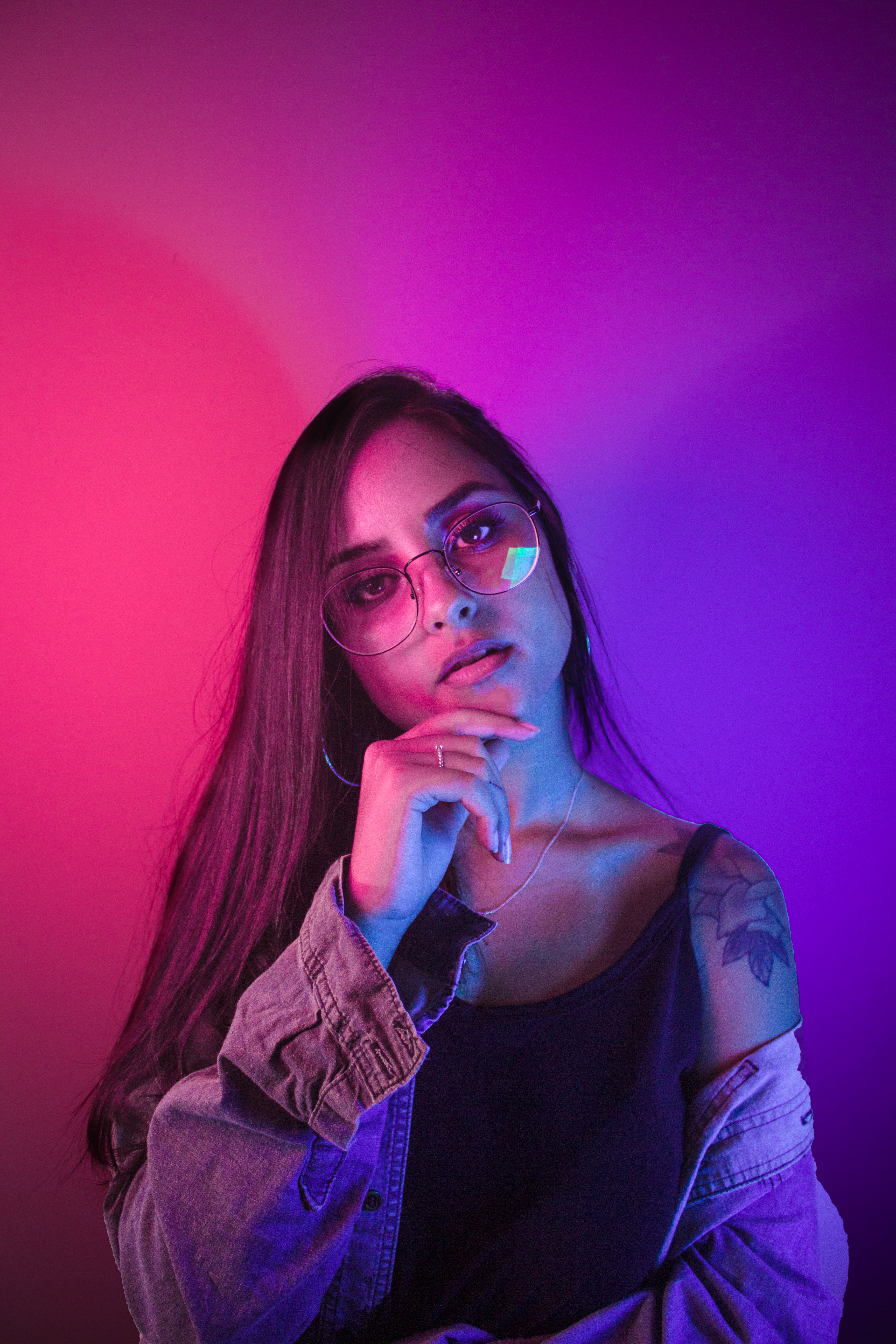 A woman wearing glasses, posing with her hand to her chin