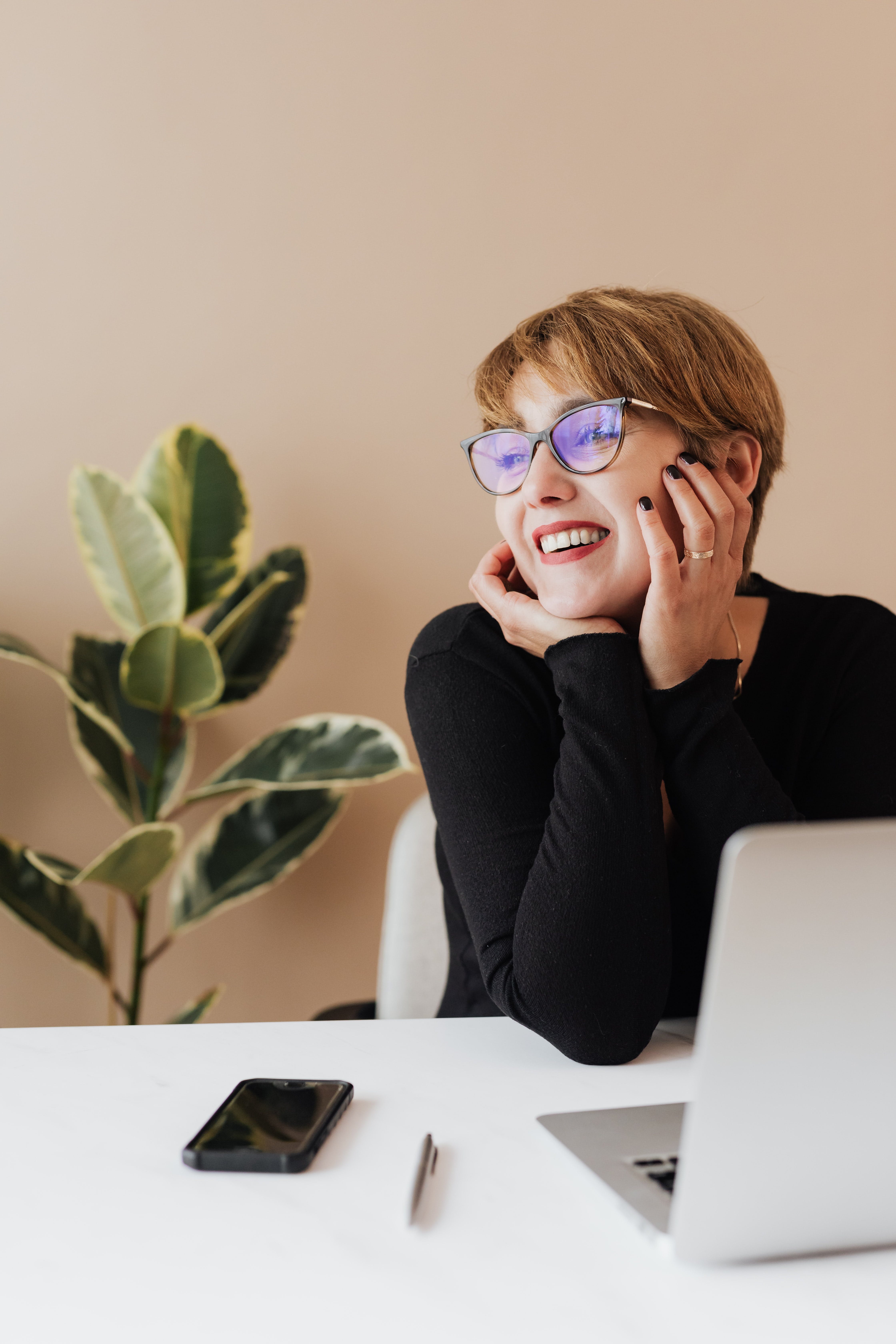 A woman sitting in front of a laptop, wearing glasses